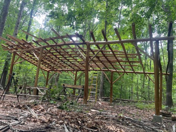 Wooden structure under construction in a green forest setting.