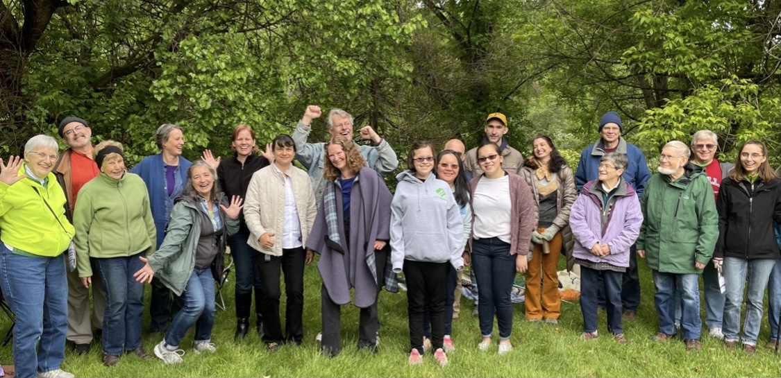 Group of diverse people outdoors in a green forest setting for community event.