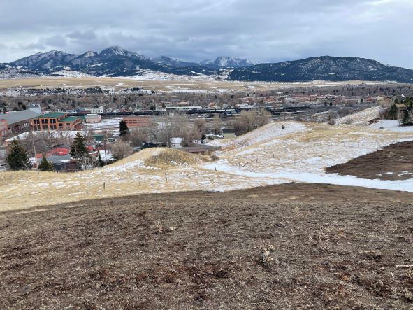 Scenic view of mountains, town, and open fields in winter.