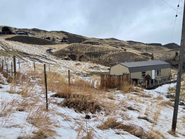 Rural landscape with a small house on a hillside in winter.