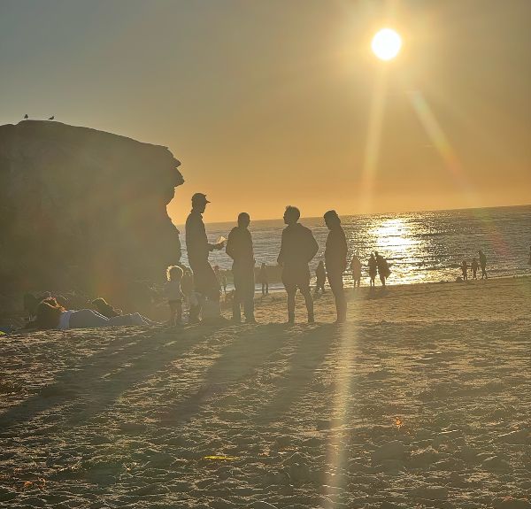 People enjoying sunset at Santa Cruz beach with cliffs and ocean view.