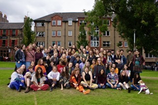 Large diverse group of people gathered outdoors in front of residential buildings.