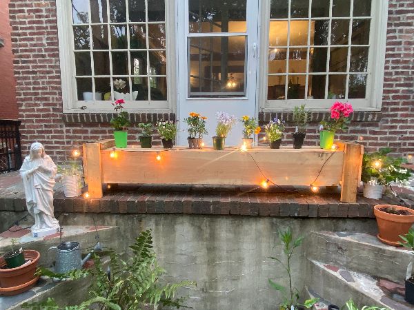 Decorative window box with potted plants and string lights in a cozy outdoor setting.