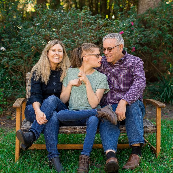 Three people sitting on a garden bench, smiling and talking.