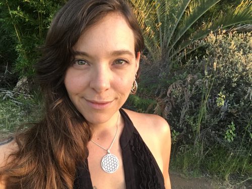 Portrait of a woman outdoors with lush greenery in the background.