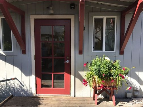 Front door of a community building with a flower planter outside.