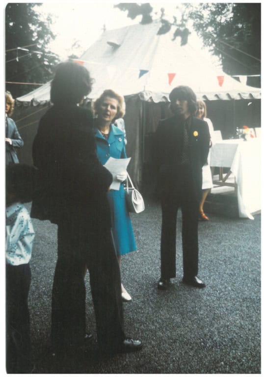 People talking at an outdoor community event with a tent in the background.