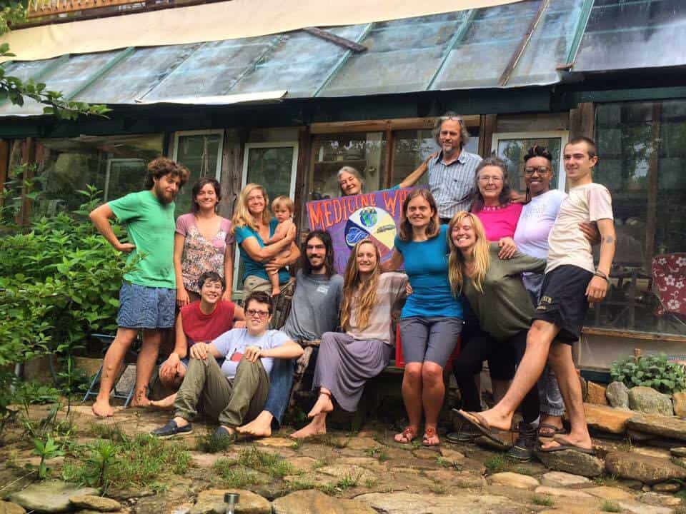 Group of diverse people smiling outside a community building at Foundation for Intentional Community.