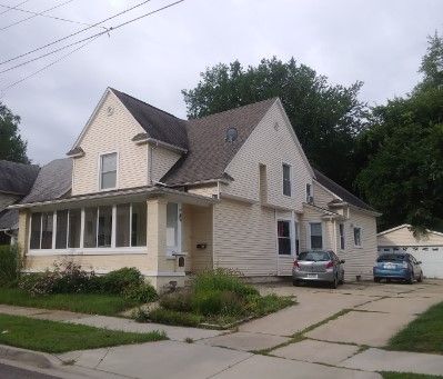 Nizhoni House with a large porch and multiple cars parked outside.