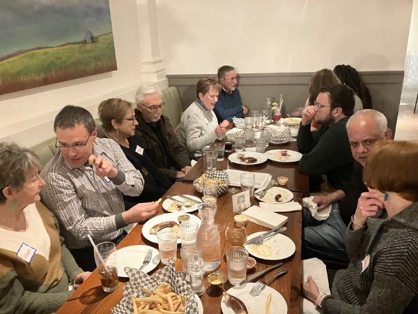 Group of people dining together at a long table in a cozy restaurant.