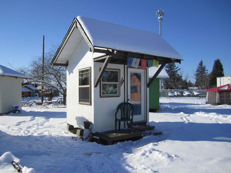 Small white community building in snowy landscape with colorful prayer flags.