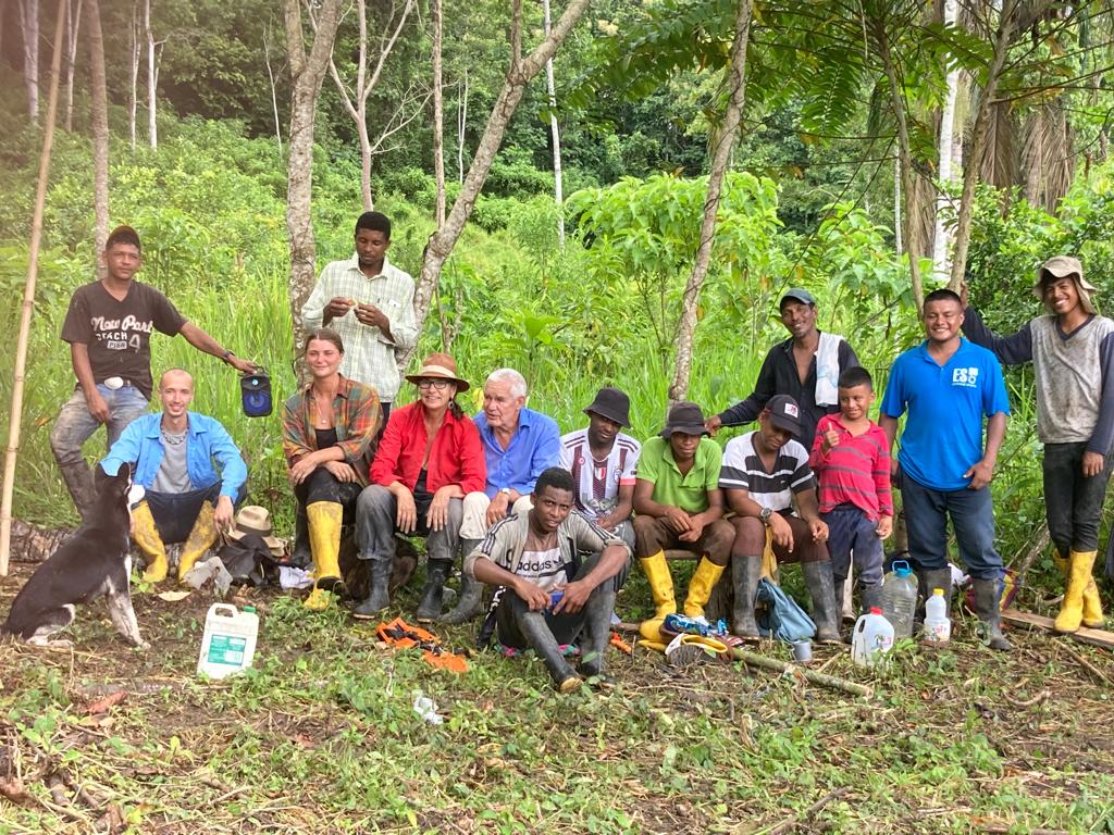 Group of diverse people planting trees in a lush forest setting.