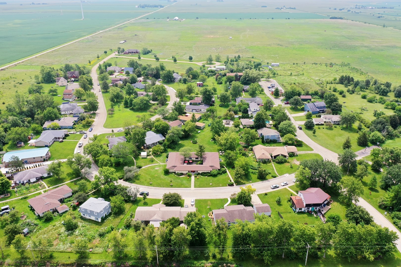 Aerial view of a peaceful intentional community with houses, roads, and lush greenery.