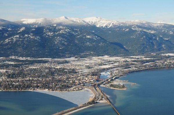 Scenic view of snow-capped mountains and a lake with a bridge in the foreground.