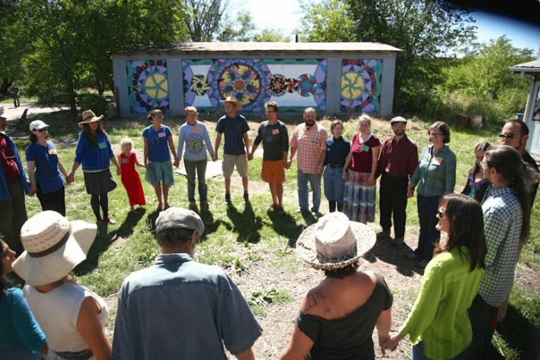 Group of people standing in a circle outdoors at Foundation for Intentional Community event.