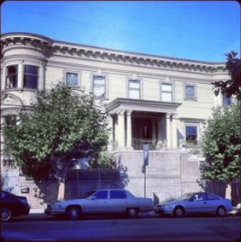 Historic white building with columns and trees in front, under a clear blue sky.