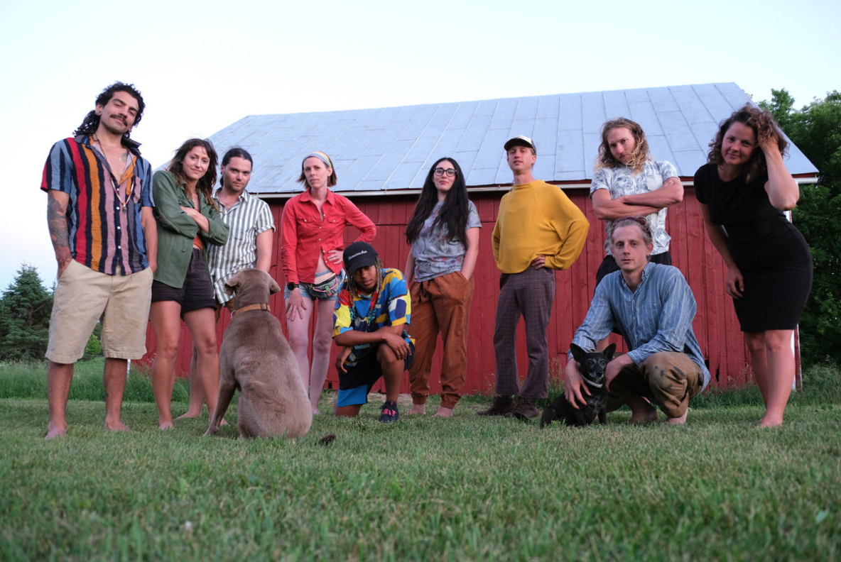Group of diverse people with a dog in front of a barn at Greenbush Growing Cooperative.