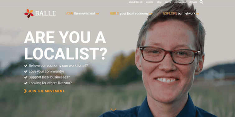 Smiling woman with glasses outdoors, promoting local economy and community support.