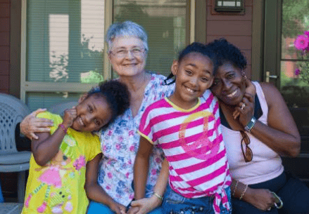 Diverse group of women and children smiling outdoors at Foundation for Intentional Community.