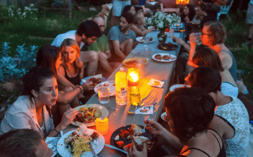 People enjoying outdoor dinner at a community gathering in the evening.