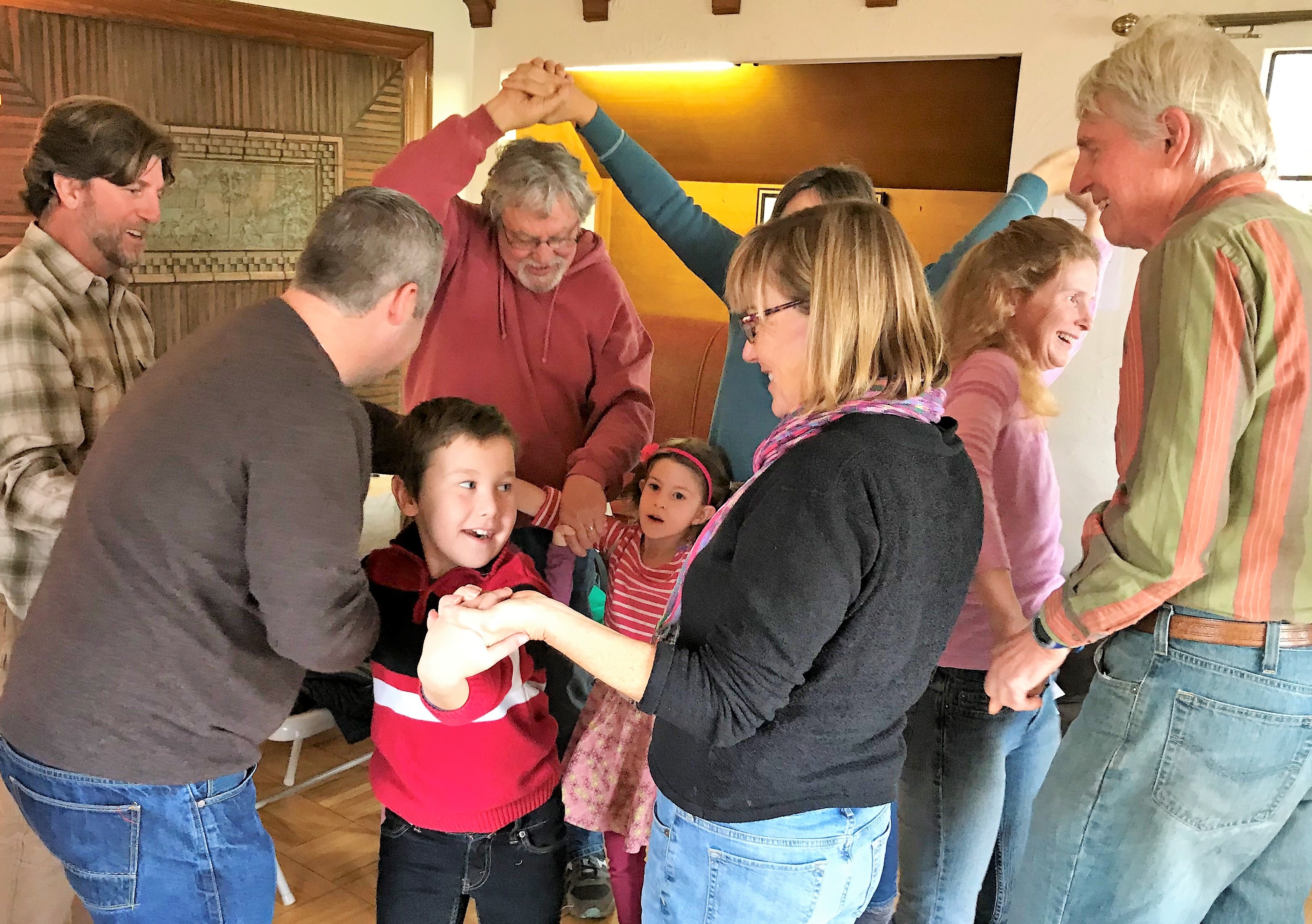 Group of people dancing and playing together indoors at a community gathering.