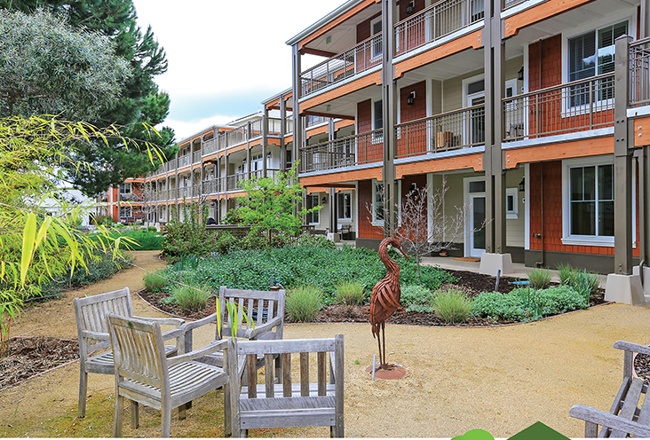 Exterior view of Mountain View Cohousing Community with landscaped garden and seating area.