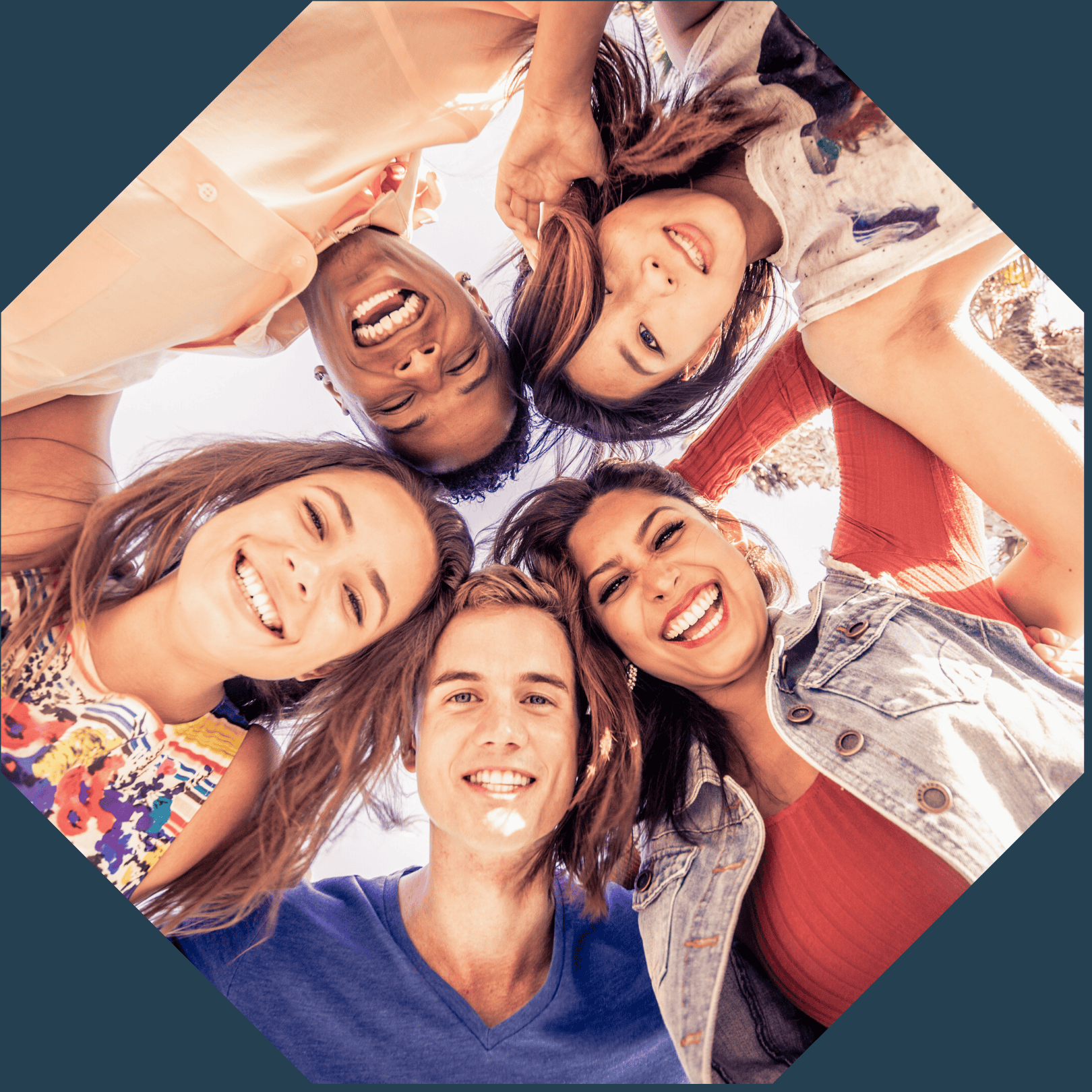 Diverse group of young people smiling in a circle outdoors.