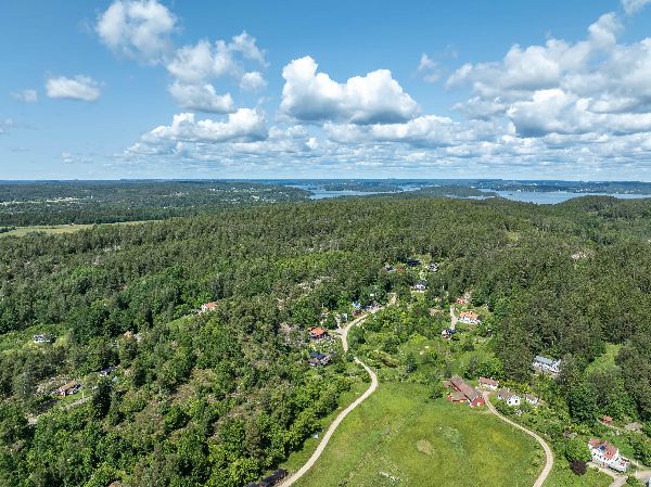Aerial view of Utsikten Ecovillage surrounded by lush green forests and blue skies.