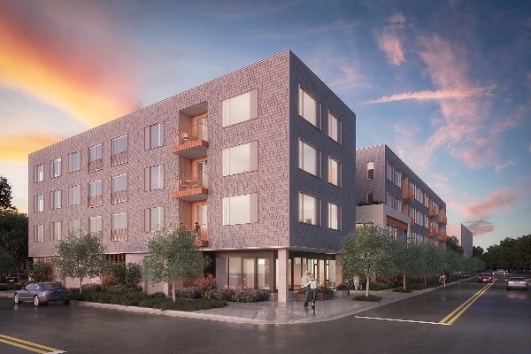 Modern cohousing building at sunset with trees and street view.