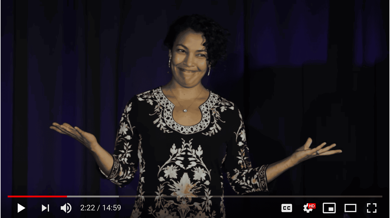 Smiling woman on stage at Foundation for Intentional Community event.
