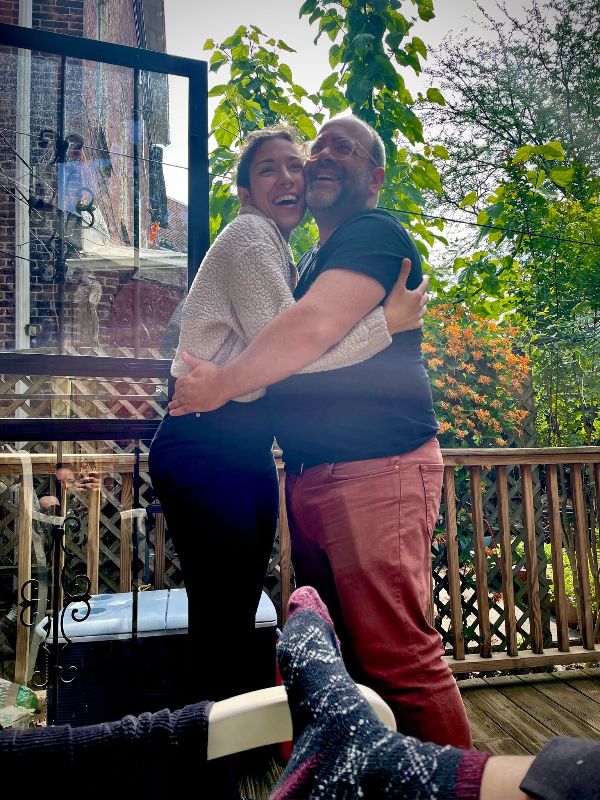 Happy couple embracing outdoors in a garden with trees and a wooden deck.