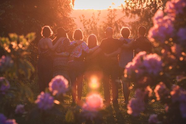 Group of people holding hands in a circle during sunset at Wildfern Grove.
