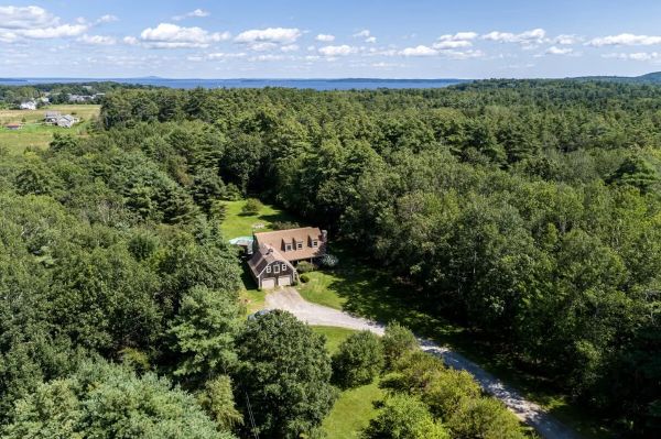 A house surrounded by dense green trees in a rural setting.