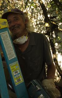Man smiling outdoors with sunlight filtering through trees.