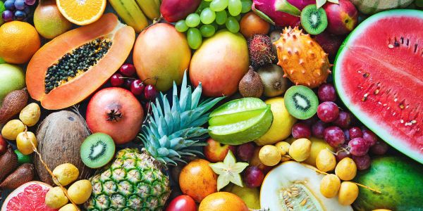 Colorful assortment of fresh tropical fruits including watermelon, pineapple, kiwi, and papaya.