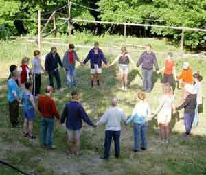 Group of people holding hands in a circle outdoors at a community gathering.