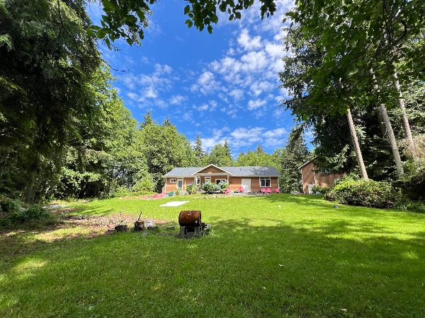 Scenic view of a house surrounded by lush green trees and a well-maintained lawn.