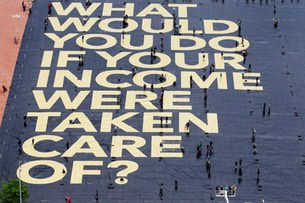 Large public art installation with text asking about income care in a city square.