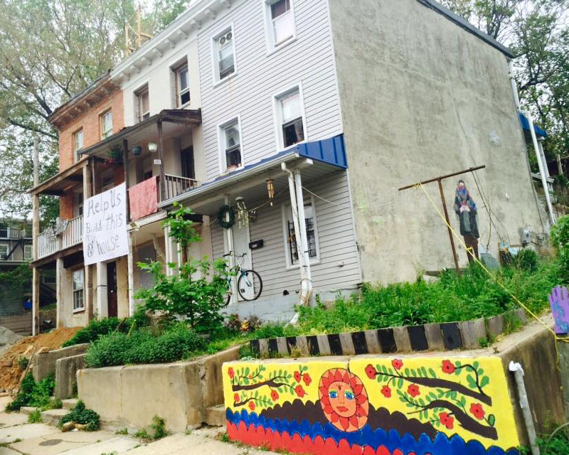 Community housing with colorful mural and handmade sign for help.