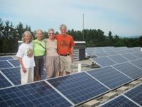 Group of people standing near solar panels at a community project site.
