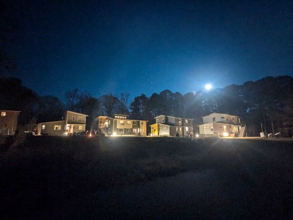 Night view of a community with illuminated houses under a bright moon.