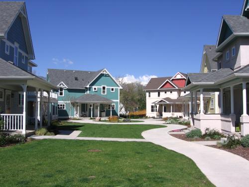 Colorful houses in a community with green lawn and clear blue sky.