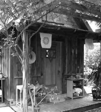 Rustic wooden tiny house with outdoor decor and plants.
