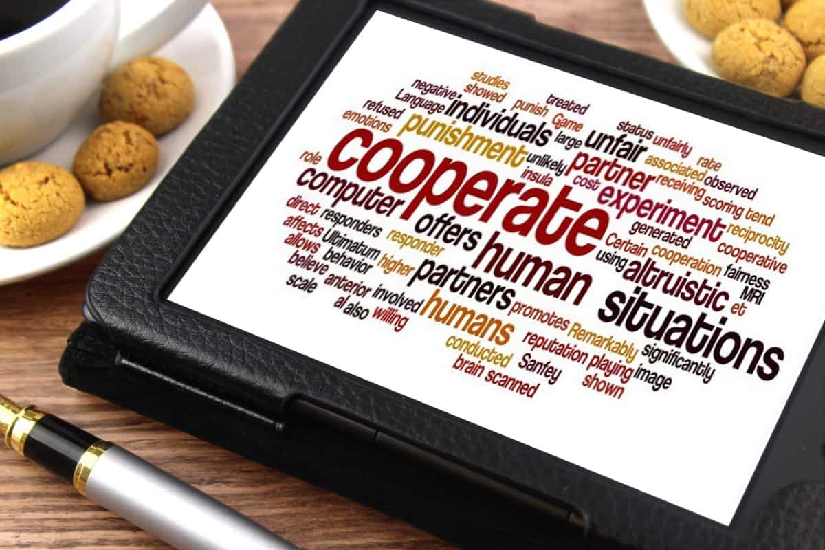 Word cloud on tablet screen emphasizing 'cooperate' and 'humans' for community collaboration.