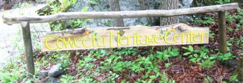 Coweeta Heritage Center sign in a wooded area with greenery.