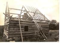 Historical photo of log cabin under construction at the Foundation for Intentional Community.