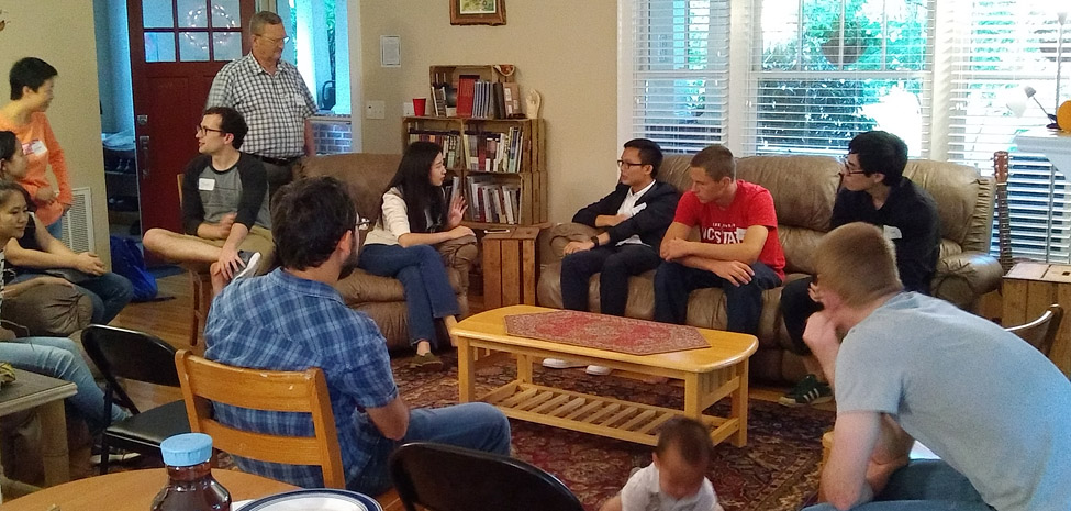 Group of people in a cozy living room engaged in discussion.