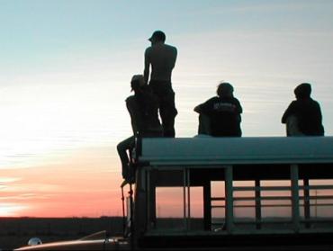 Group of young people watching sunset from a rooftop.
