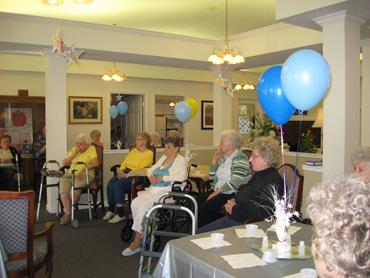 Elderly people attending a community gathering in a decorated room.