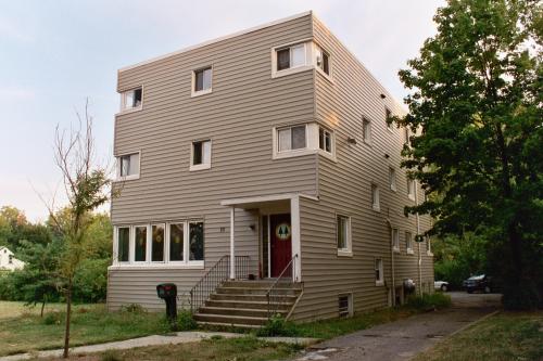 Multi-story residential building with beige siding and front steps.